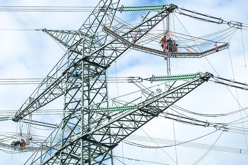 Arbeiter auf Strommast symbolisiert Netze und Netzausbau