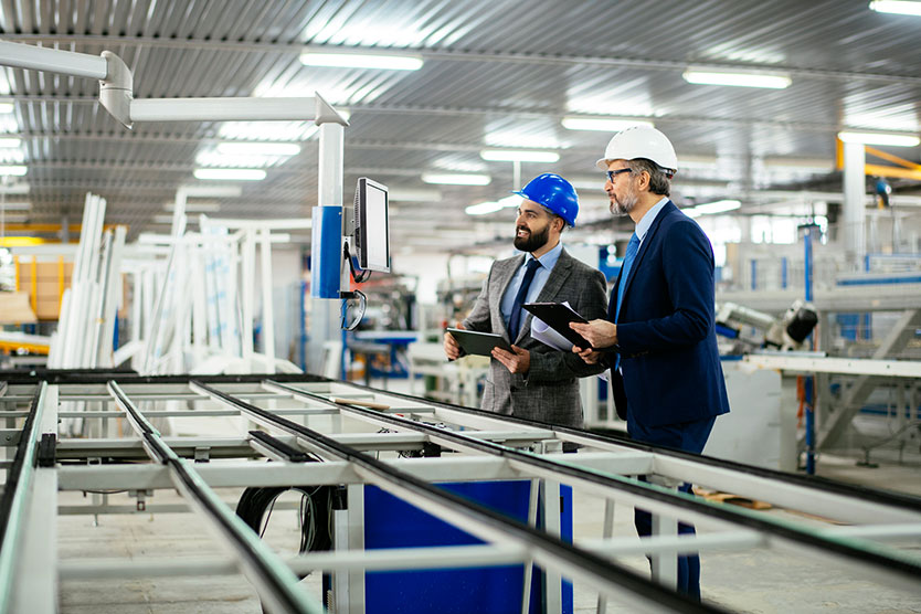 Arbeiter schauen in einer Fabrik auf einen Monintor, symbolisiert Energieberatung und -förderung für Unternehmen