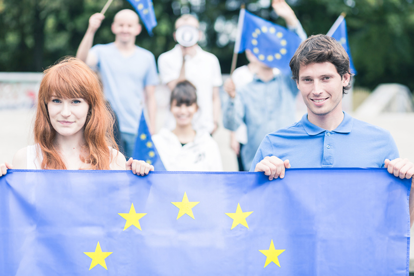Junge Menschen halten die EU-Flagge zum Theme EU-Werte und Wirtschaftsgemeinschaft; Quelle: Fotolia.com/Photographee.eu