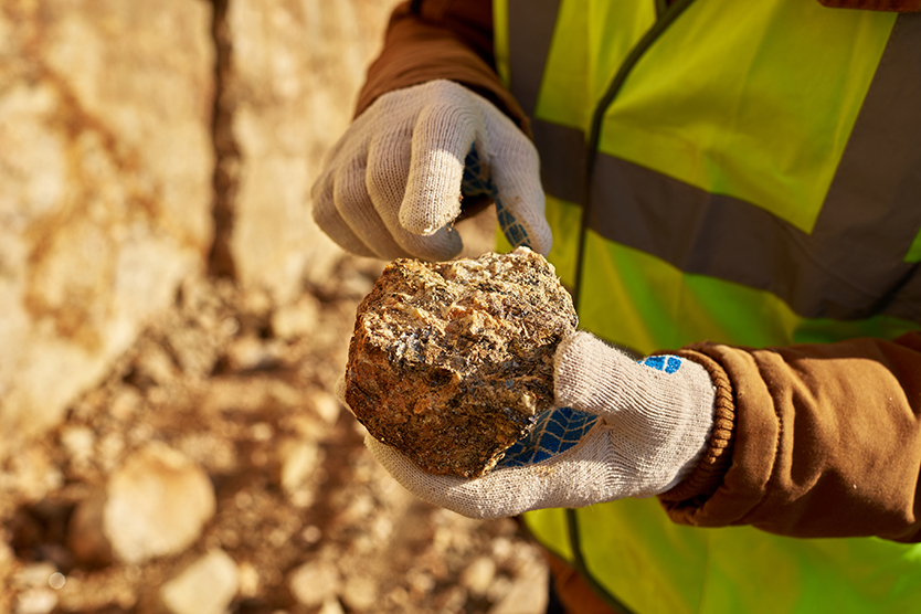Bergmann hält ein Stück Mineral in der Hand, symbolisiert das Thema Rohstoffe und Ressourcen