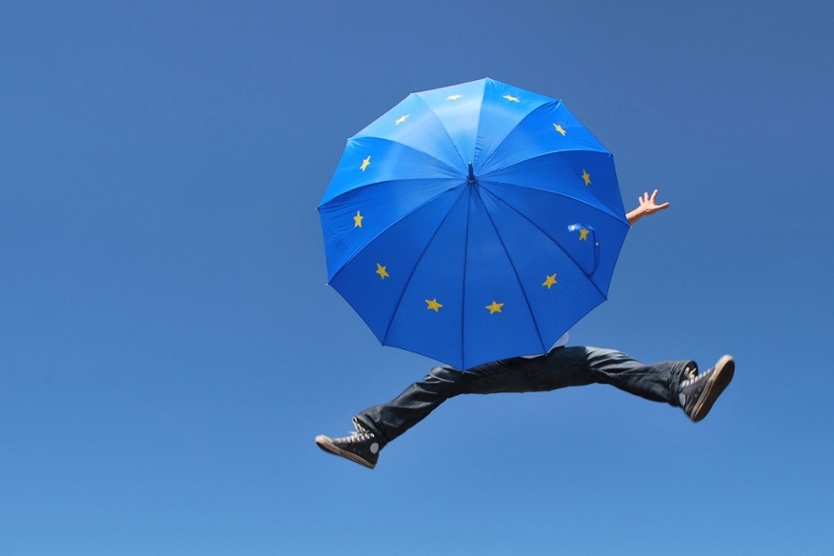 Mann springt mit EU-Regenschirm