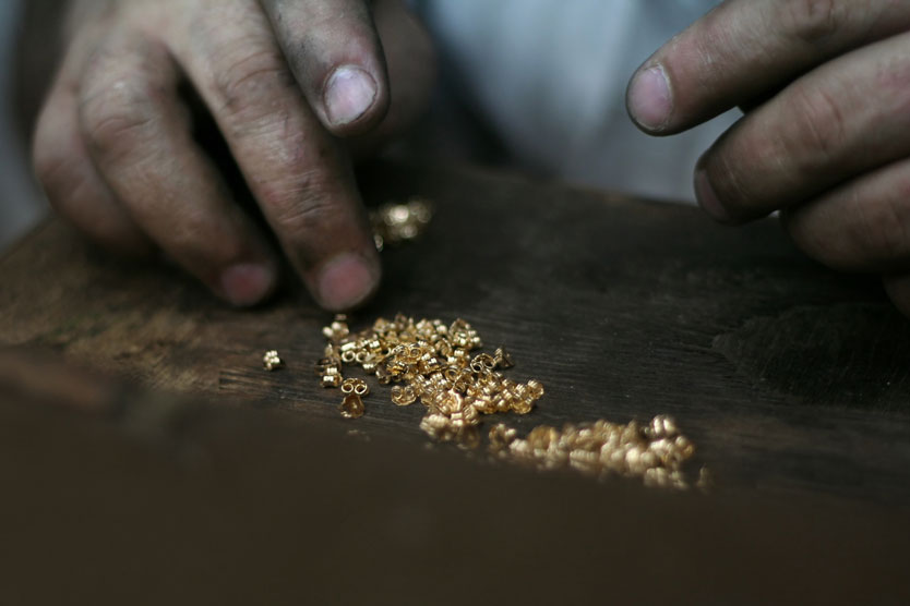 Mann zählt kleine Goldstückchen zum Thema "Konfliktrohstoffe"