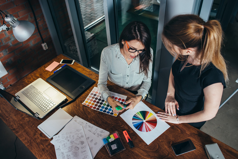 Zwei kreative Designerinnen, die Auswahl der Farben mit Farbpalette im Büro arbeiten