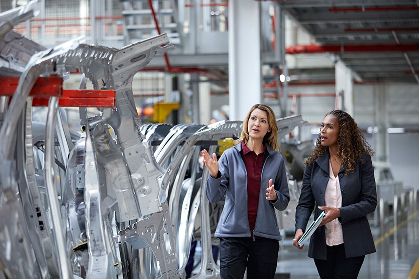 Zwei Ingeneurinnen unterhalten sich in einer Autofabrik