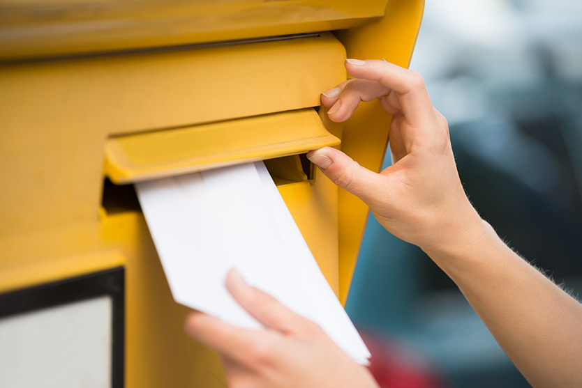 Hand wirft Brief in Briefkasten ein
