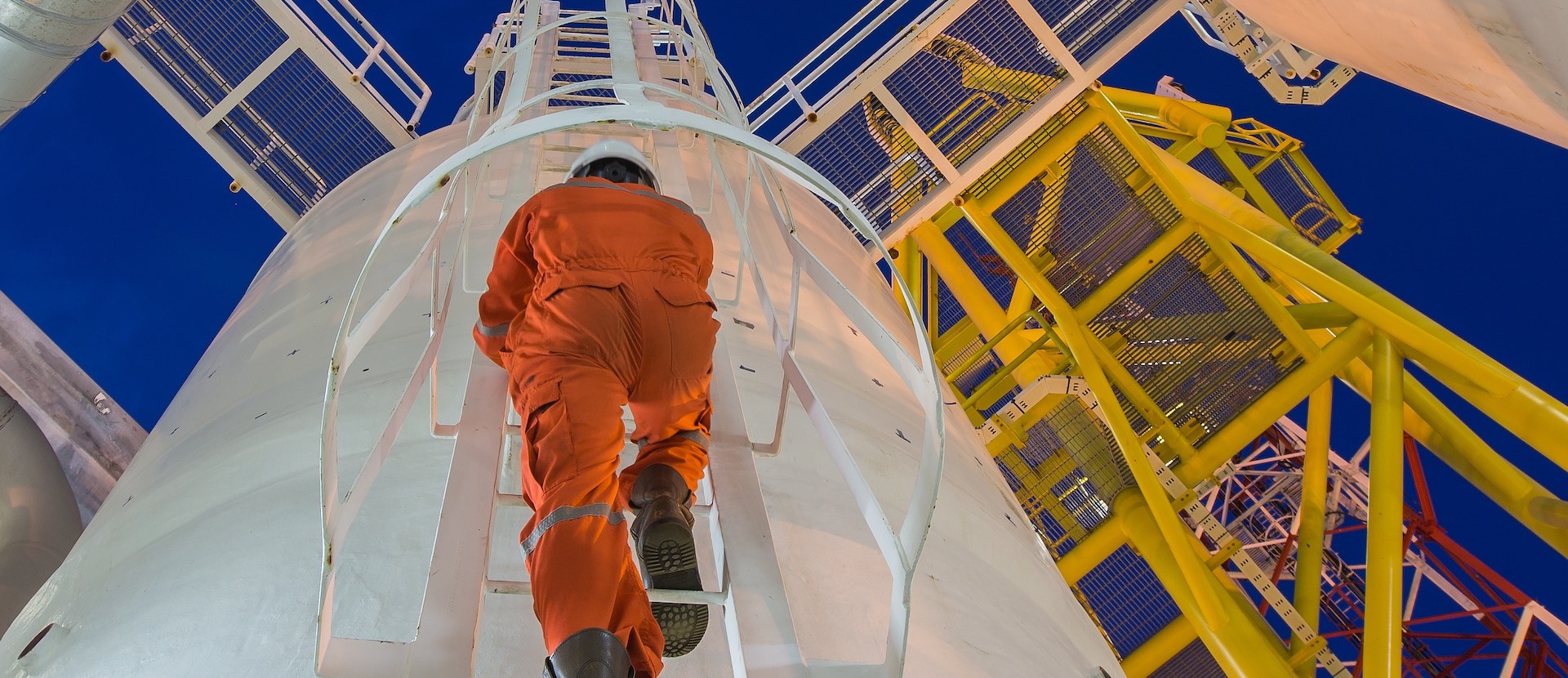 Person im Sicherheitskleidung klettert einen Turm in einem Gaskraftwerk hoch