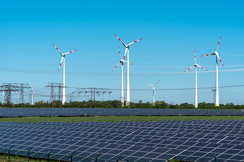 Solar installation, wind turbines and electricity pylons symbolising the energy transition
