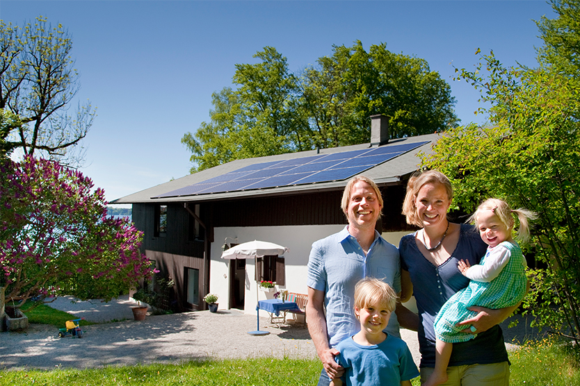 A family stands in front of their house with solar roof, symbolizing Germany makes it efficient