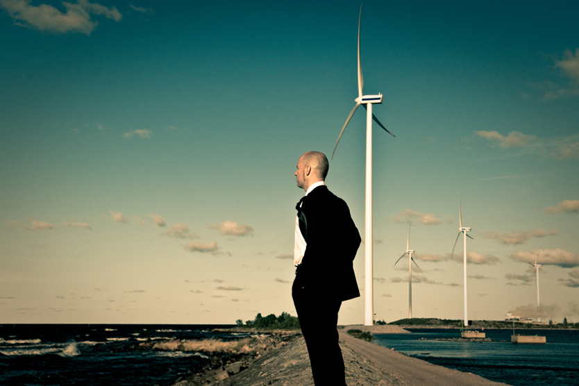 Man at the sea in front of wind turbines; Source: istockphoto.com/ferrantraite